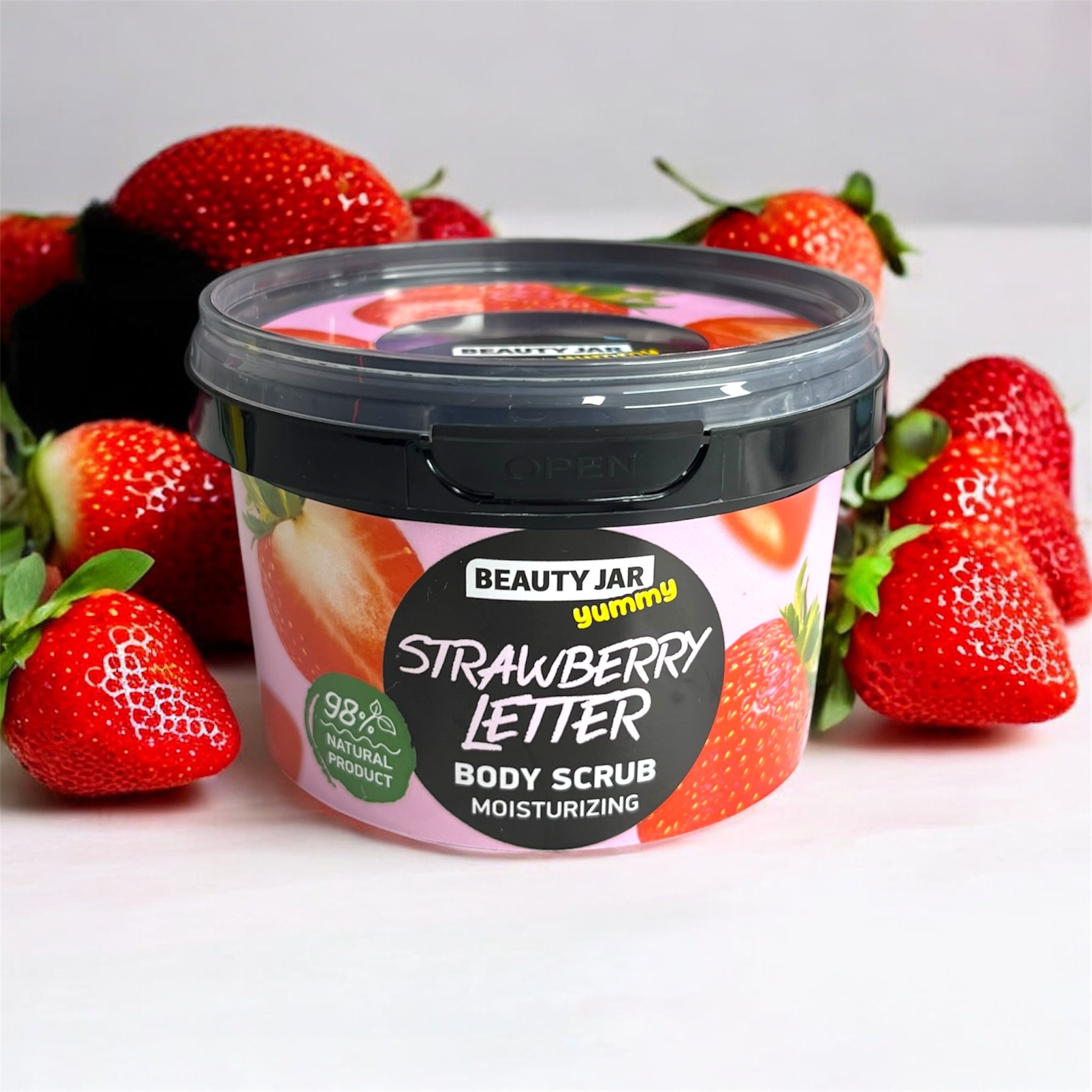 Gommage corps Beauty Jar Strawberry Letter 360 g, pot illustré de fraises avec couvercle noir, 98% naturel, entouré de vraies fraises rouges.