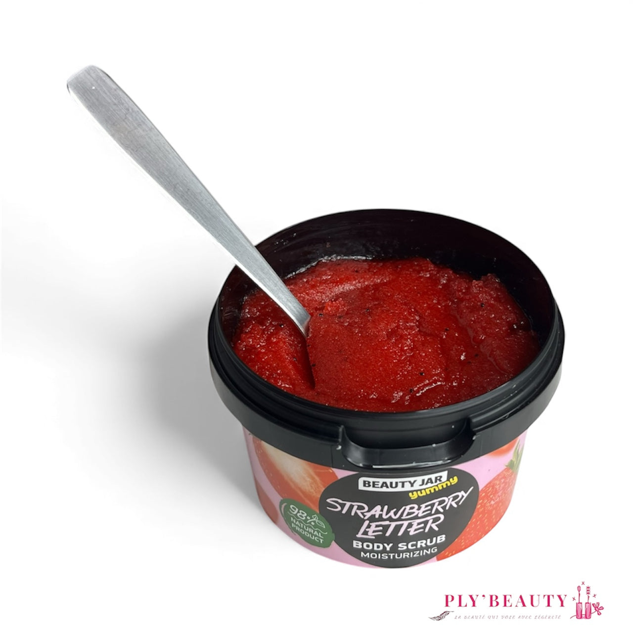 Gommage corps Beauty Jar Strawberry Letter 360 g ouvert, texture rouge brillante avec cuillère, exfoliant hydratant à la fraise dans pot noir.
